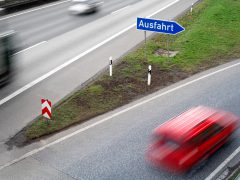 Een rode auto rijdt over een snelweg in Duitsland.
