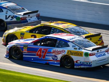 Drie NASCAR-auto's racen op een circuit.