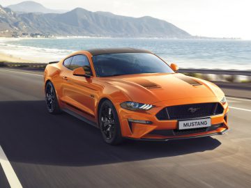 De Mustang uit 2019 rijdt op een weg vlakbij de oceaan.