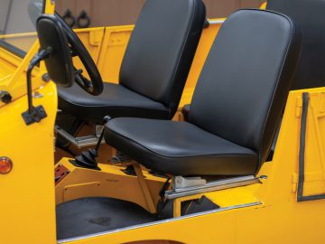 Het interieur van een gele cabriolet-jeep met zwarte stoelen.