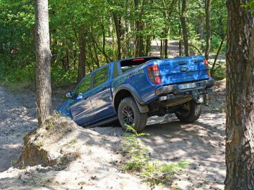 Een blauwe Ford Ranger rijdt door een bosrijke omgeving in een scène die doet denken aan "Fast & Furious: Hobbs & Shaw".