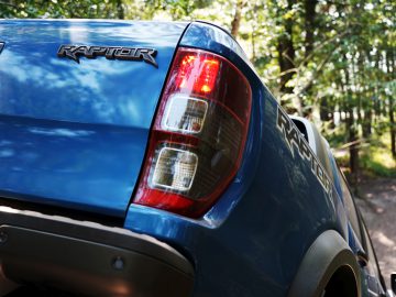 De achterkant van een blauwe pick-up op een onverharde weg, die doet denken aan een scène uit Fast & Furious: Hobbs & Shaw.