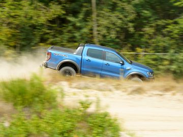Een blauwe Ford Ranger rijdt over een onverharde weg in een scène die doet denken aan "Fast & Furious: Hobbs & Shaw".
