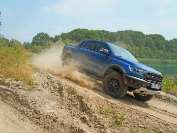 Een blauwe Ford Ranger rijdt over een onverharde weg in een scène die doet denken aan "Fast & Furious: Hobbs & Shaw.