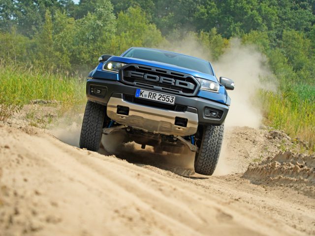 Een blauwe Ford Raptor uit "Fast & Furious: Hobbs & Shaw" rijdt over een onverharde weg.