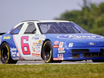 Een blauw-witte NASCAR-auto die op een circuit rijdt.