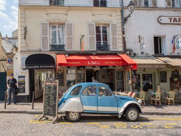 Een blauwe auto geparkeerd voor een gebouw in Frankrijk.
