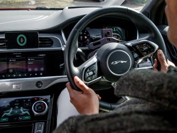 Er zit een persoon op de bestuurdersstoel van een Jaguar Land Rover.