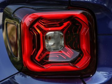 Het achterlicht van een blauwe Jeep Renegade met een jerrycan.