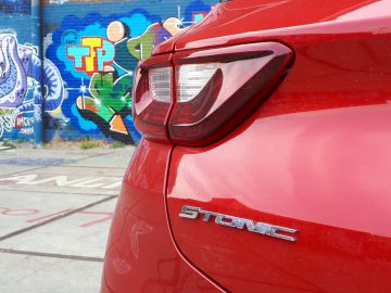 De achterkant van een rode Kia Stonic geparkeerd voor een graffitimuur.