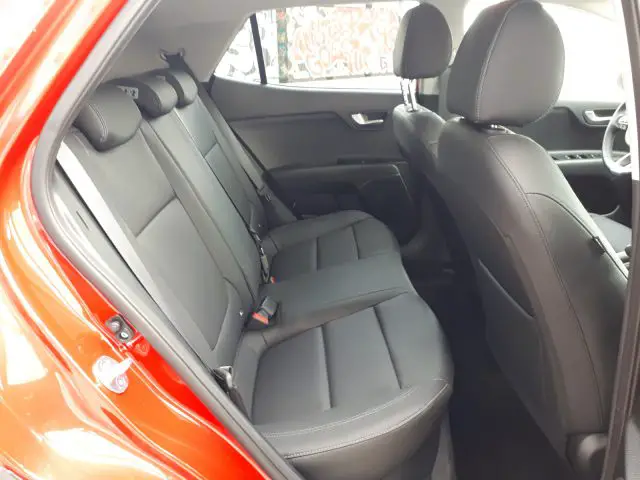 De achterbank van een rode Kia Stonic met zwarte stoelen.