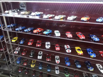 Een tentoonstelling van Le Mans-speelgoedauto's in een glazen kast.
