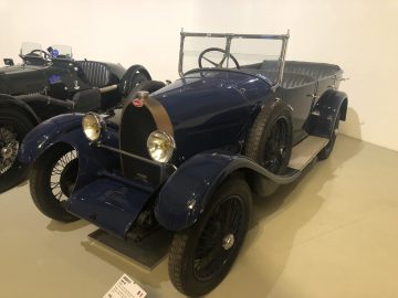 Een blauwe vintage Le Mans-auto staat tentoongesteld in een museum.