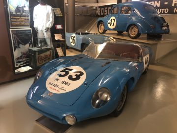 In een museum staat een blauwe Le Mans-raceauto tentoongesteld.