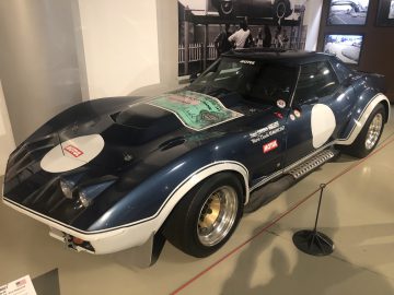 Een blauw-witte Le Mans-sportwagen staat tentoongesteld in een museum.