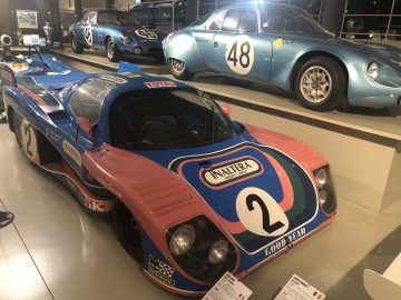 In een museum staat een blauw-roze Le Mans-raceauto tentoongesteld.