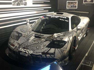 Een zilveren Le Mans-sportwagen staat tentoongesteld in een museum.