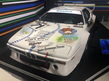Een witte BMW M3 Le Mans staat tentoongesteld in een museum.