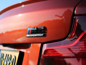 Een close-up van een rode BMW M2 Competition met een badge erop.