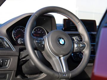 Het stuur van een rode auto van BMW M2 Competition.