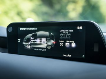 Het dashboard van een Mazda 3 met een display van een auto.