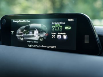 Het dashboard van een Mazda 3 met een display waarop een auto te zien is.