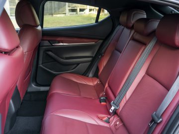 De achterbank van een Mazda 3 met rood lederen stoelen.