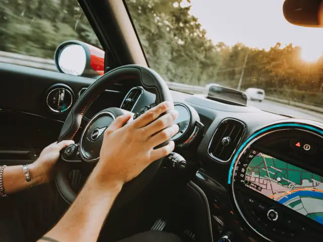 Een persoon die een MINI John Cooper Works Clubman bestuurt met een GPS op het dashboard.