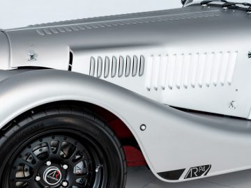 Op een witte achtergrond wordt een Morgan Plus 4-sportwagen weergegeven.
