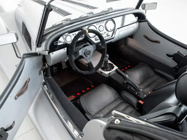 Het interieur van een Morgan Plus 4 sportwagen met lederen stoelen en stuurwiel.