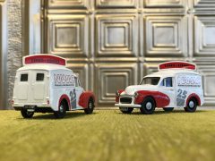 Twee Morris Minor speelgoed-ijscowagentjes op een vloerbedekking.