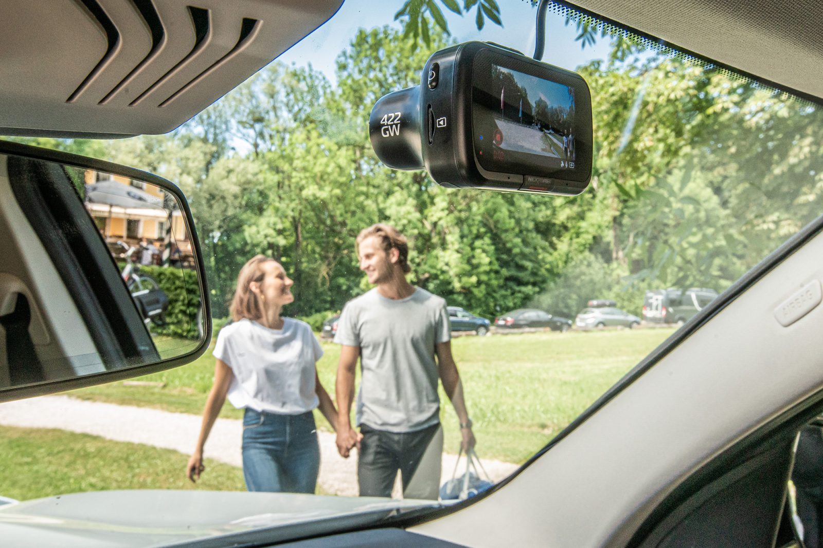 Een man en een vrouw staan met een dashcam voor een auto.