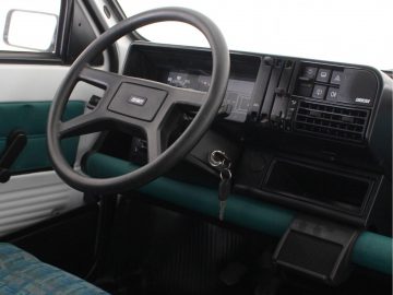 Het interieur van een busje met een stuur en dashboard in panda-thema.