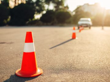 Verkeerskegels op de weg voor een auto bij rijschoolnamen.