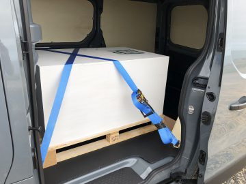 De achterkant van een Renault Trafic-busje met een doos erin.