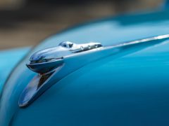 Een close-up van het motorkapornament op een blauwe Tucker-auto.