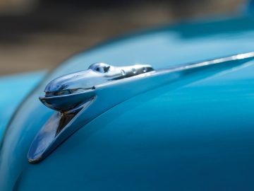 Een close-up van het motorkapornament op een blauwe Tucker-auto.