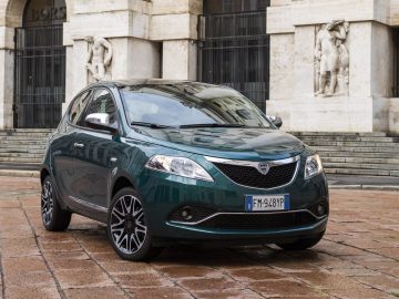 Een groene Lancia geparkeerd voor een gebouw.