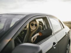 Een jonge vrouw zit op de bestuurdersstoel van een auto en denkt na over haar autoverzekering.