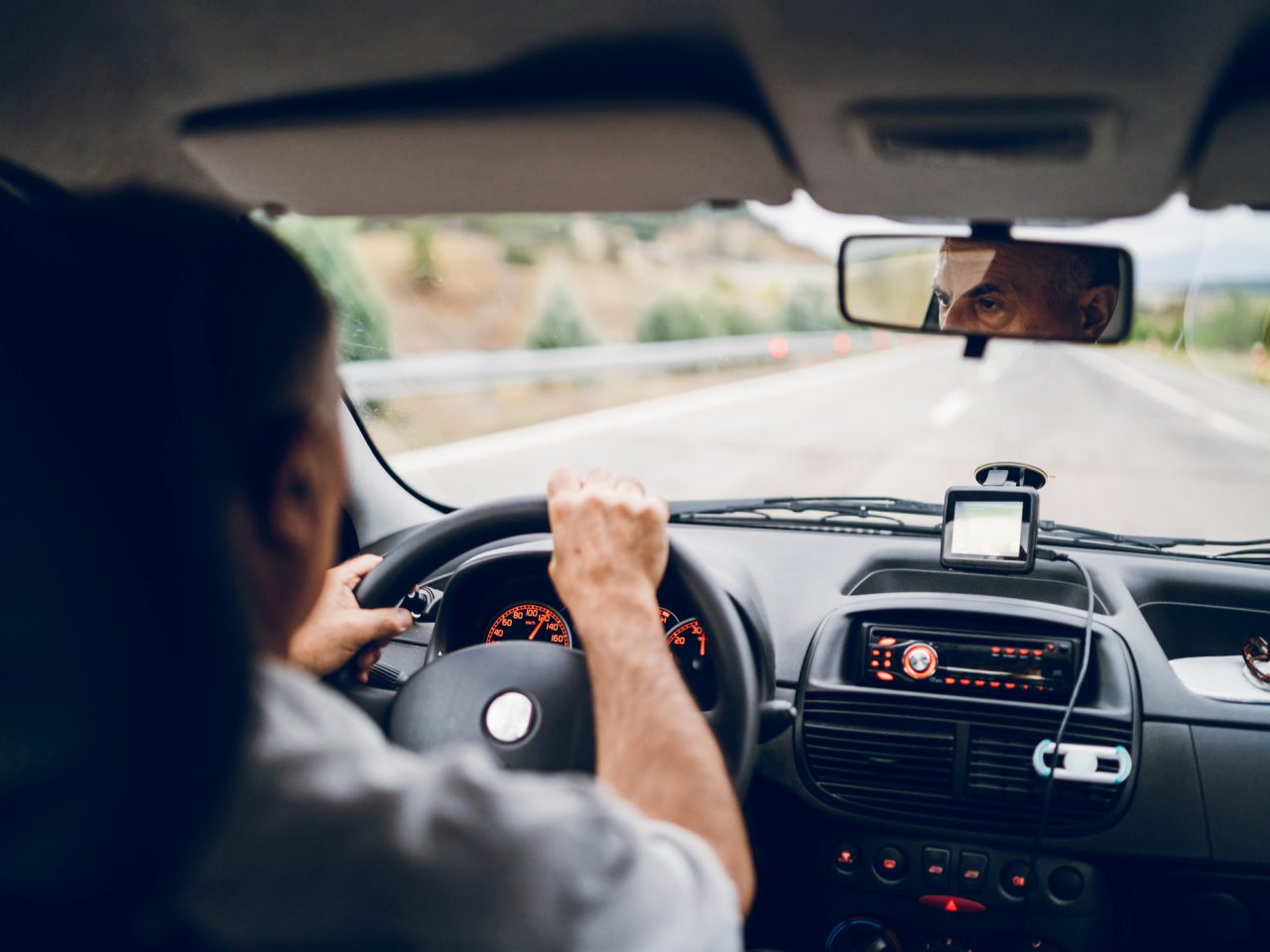 Een man die op spannende wijze autorijdt op een snelweg.