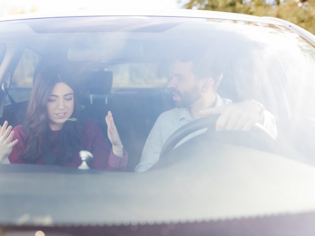 Een man en vrouw bespreken rijgedrag in een auto.