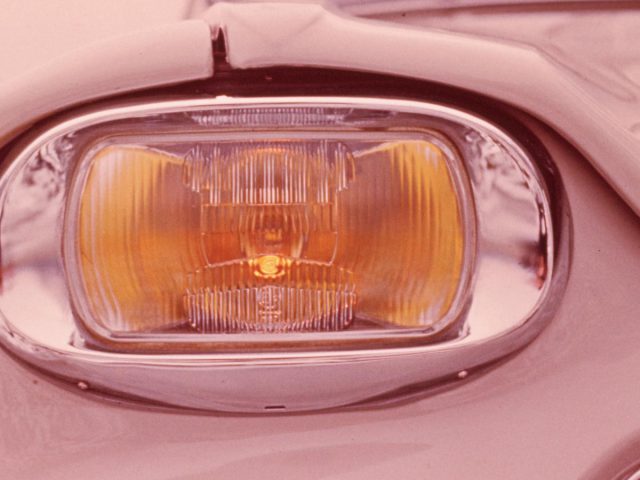 Een close-up van de koplampen van een roze auto.