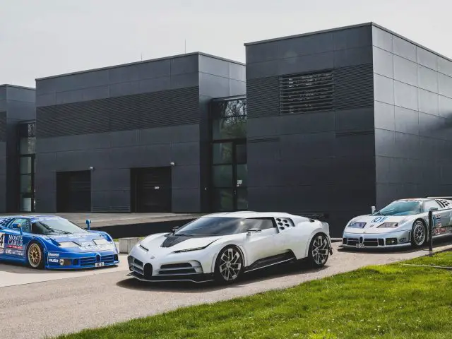 Drie Bugatti Centodieci-sportwagens geparkeerd voor een gebouw.