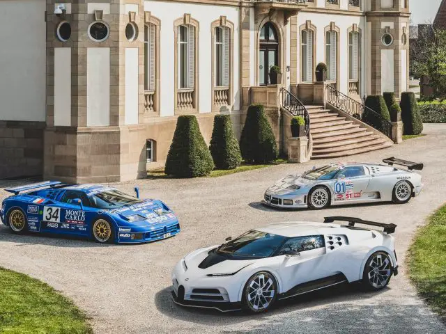 Drie Bugatti Centodieci-sportwagens geparkeerd voor een herenhuis.