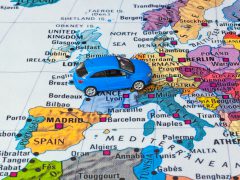 Een speelgoedauto bovenop een kaart van Europa, gemarkeerd met een milieusticker.