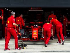 Een groep mannen werkt aan een door Shell gesponsorde Ferrari-raceauto.