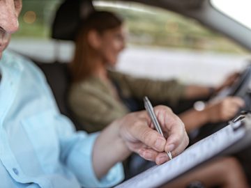 Een man in een auto-actief huftergedrag terwijl hij op een klembord schrijft.
