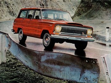 Een rode Jeep Wagoneer rijdt over een weg.