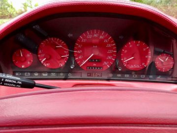Het dashboard van een rode Mercedes-Benz SL500 Carat van Duchatelet sportwagen.