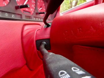 Het interieur van een rode Mercedes-Benz SL500 Carat van Duchatelet met een rood stuur.